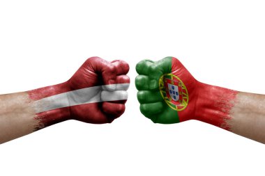 Two hands punch to each others on white background. Country flags painted fists, conflict crisis concept between latvia and portugal