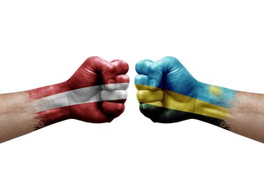 Two hands punch to each others on white background. Country flags painted fists, conflict crisis concept between latvia and rwanda