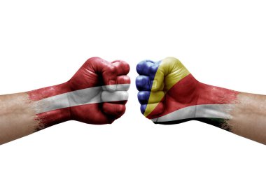 Two hands punch to each others on white background. Country flags painted fists, conflict crisis concept between latvia and seychelles