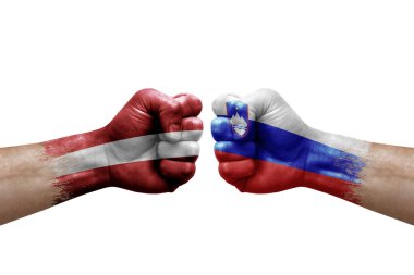 Two hands punch to each others on white background. Country flags painted fists, conflict crisis concept between latvia and slovenia