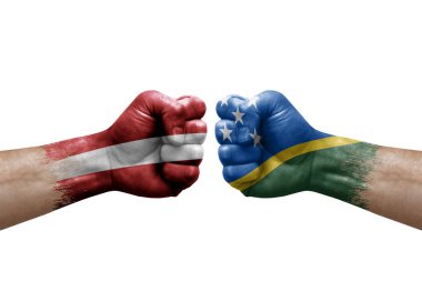 Two hands punch to each others on white background. Country flags painted fists, conflict crisis concept between latvia and solomon islands