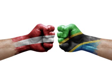 Two hands punch to each others on white background. Country flags painted fists, conflict crisis concept between latvia and tanzania