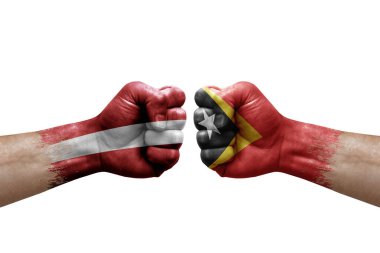 Two hands punch to each others on white background. Country flags painted fists, conflict crisis concept between latvia and timor leste