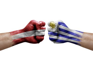 Two hands punch to each others on white background. Country flags painted fists, conflict crisis concept between latvia and uruguay