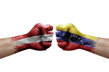 Two hands punch to each others on white background. Country flags painted fists, conflict crisis concept between latvia and venezuela