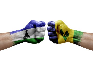 Two hands punch to each others on white background. Country flags painted fists, conflict crisis concept between lesotho and saint vincent and the grenadines