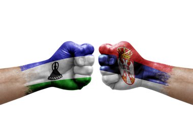 Two hands punch to each others on white background. Country flags painted fists, conflict crisis concept between lesotho and serbia