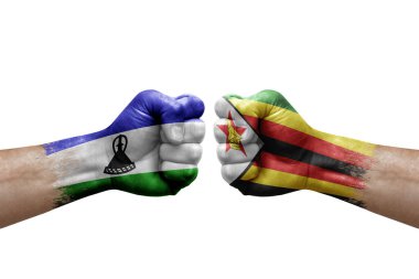 Two hands punch to each others on white background. Country flags painted fists, conflict crisis concept between lesotho and zimbabwe