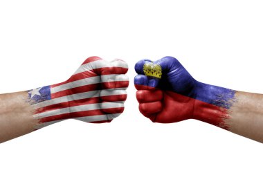 Two hands punch to each others on white background. Country flags painted fists, conflict crisis concept between liberia and liechtenstein