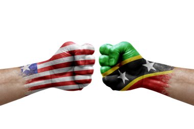 Two hands punch to each others on white background. Country flags painted fists, conflict crisis concept between liberia and saint kitts and nevis