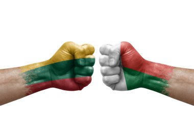 Two hands punch to each others on white background. Country flags painted fists, conflict crisis concept between lithuania and madagascar
