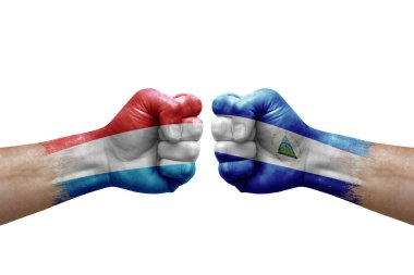 Two hands punch to each others on white background. Country flags painted fists, conflict crisis concept between luxembourg and nicaragua
