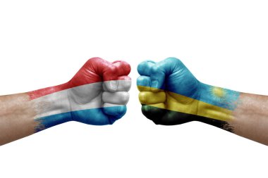 Two hands punch to each others on white background. Country flags painted fists, conflict crisis concept between luxembourg and rwanda
