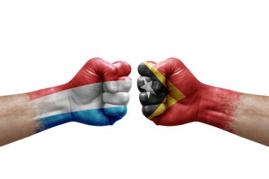 Two hands punch to each others on white background. Country flags painted fists, conflict crisis concept between luxembourg and timor leste
