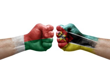 Two hands punch to each others on white background. Country flags painted fists, conflict crisis concept between madagascar and mozambique