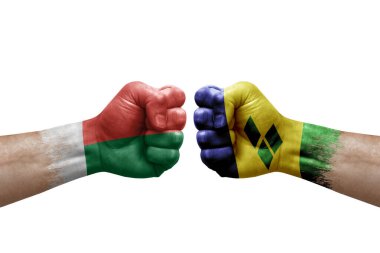 Two hands punch to each others on white background. Country flags painted fists, conflict crisis concept between madagascar and saint vincent and the grenadines