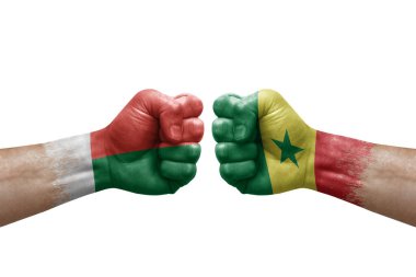 Two hands punch to each others on white background. Country flags painted fists, conflict crisis concept between madagascar and senegal