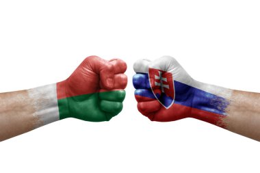 Two hands punch to each others on white background. Country flags painted fists, conflict crisis concept between madagascar and slovakia