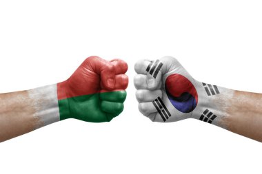 Two hands punch to each others on white background. Country flags painted fists, conflict crisis concept between madagascar and south korea