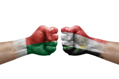 Two hands punch to each others on white background. Country flags painted fists, conflict crisis concept between madagascar and tajikistan