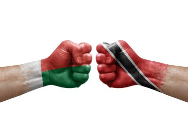 Two hands punch to each others on white background. Country flags painted fists, conflict crisis concept between madagascar and tobago