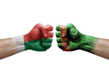 Two hands punch to each others on white background. Country flags painted fists, conflict crisis concept between madagascar and turkmenistan