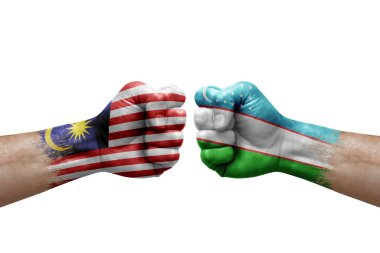 Two hands punch to each others on white background. Country flags painted fists, conflict crisis concept between malaysia and uzbekistan