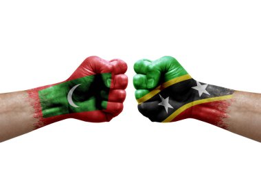 Two hands punch to each others on white background. Country flags painted fists, conflict crisis concept between maldives and saint kitts and nevis