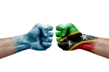 Two hands punch to each others on white background. Country flags painted fists, conflict crisis concept between micronesia and saint kitts and nevis
