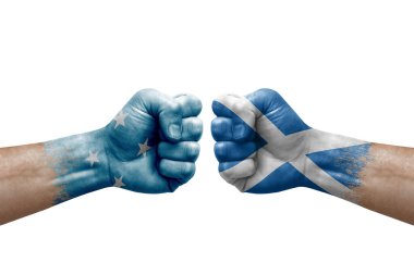 Two hands punch to each others on white background. Country flags painted fists, conflict crisis concept between micronesia and scotland