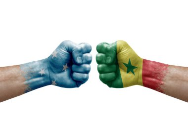 Two hands punch to each others on white background. Country flags painted fists, conflict crisis concept between micronesia and senegal