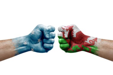 Two hands punch to each others on white background. Country flags painted fists, conflict crisis concept between micronesia and wales