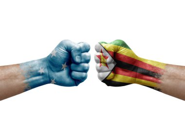 Two hands punch to each others on white background. Country flags painted fists, conflict crisis concept between micronesia and zimbabwe