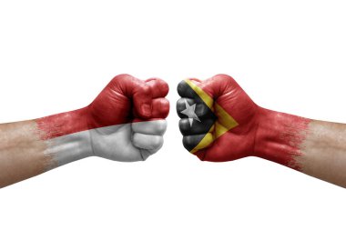 Two hands punch to each others on white background. Country flags painted fists, conflict crisis concept between monaco and timor leste