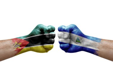 Two hands punch to each others on white background. Country flags painted fists, conflict crisis concept between mozambique and nicaragua