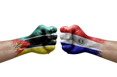 Two hands punch to each others on white background. Country flags painted fists, conflict crisis concept between mozambique and paraguay