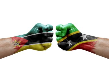 Two hands punch to each others on white background. Country flags painted fists, conflict crisis concept between mozambique and saint kitts and nevis