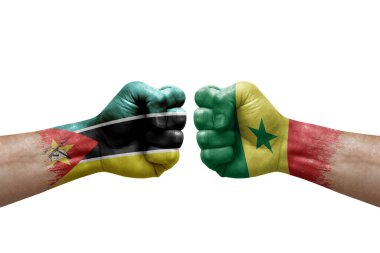 Two hands punch to each others on white background. Country flags painted fists, conflict crisis concept between mozambique and senegal