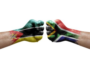 Two hands punch to each others on white background. Country flags painted fists, conflict crisis concept between mozambique and south africa