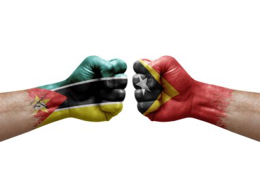 Two hands punch to each others on white background. Country flags painted fists, conflict crisis concept between mozambique and timor leste