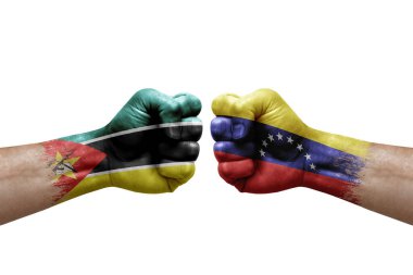 Two hands punch to each others on white background. Country flags painted fists, conflict crisis concept between mozambique and venezuela