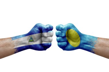Two hands punch to each others on white background. Country flags painted fists, conflict crisis concept between nicaragua and palau