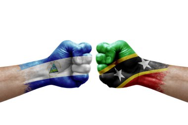 Two hands punch to each others on white background. Country flags painted fists, conflict crisis concept between nicaragua and saint kitts and nevis