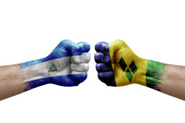 Two hands punch to each others on white background. Country flags painted fists, conflict crisis concept between nicaragua and saint vincent and the grenadines