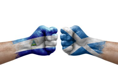 Two hands punch to each others on white background. Country flags painted fists, conflict crisis concept between nicaragua and scotland
