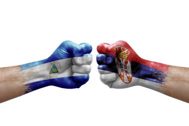 Two hands punch to each others on white background. Country flags painted fists, conflict crisis concept between nicaragua and serbia