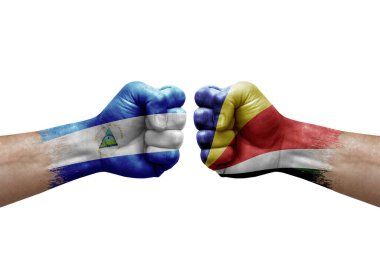 Two hands punch to each others on white background. Country flags painted fists, conflict crisis concept between nicaragua and seychelles