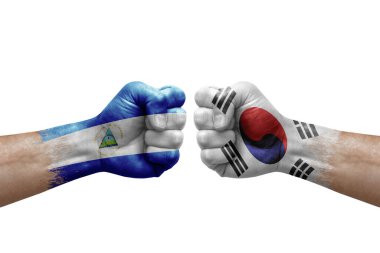 Two hands punch to each others on white background. Country flags painted fists, conflict crisis concept between nicaragua and south korea