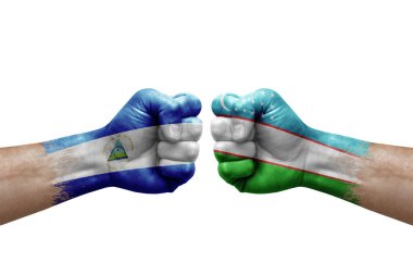Two hands punch to each others on white background. Country flags painted fists, conflict crisis concept between nicaragua and uzbekistan