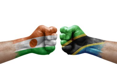 Two hands punch to each others on white background. Country flags painted fists, conflict crisis concept between niger and tanzania